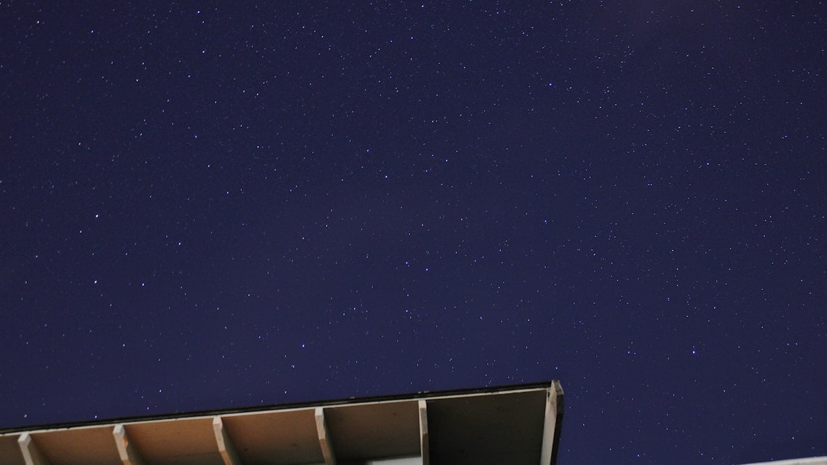 the night sky with stars above a building